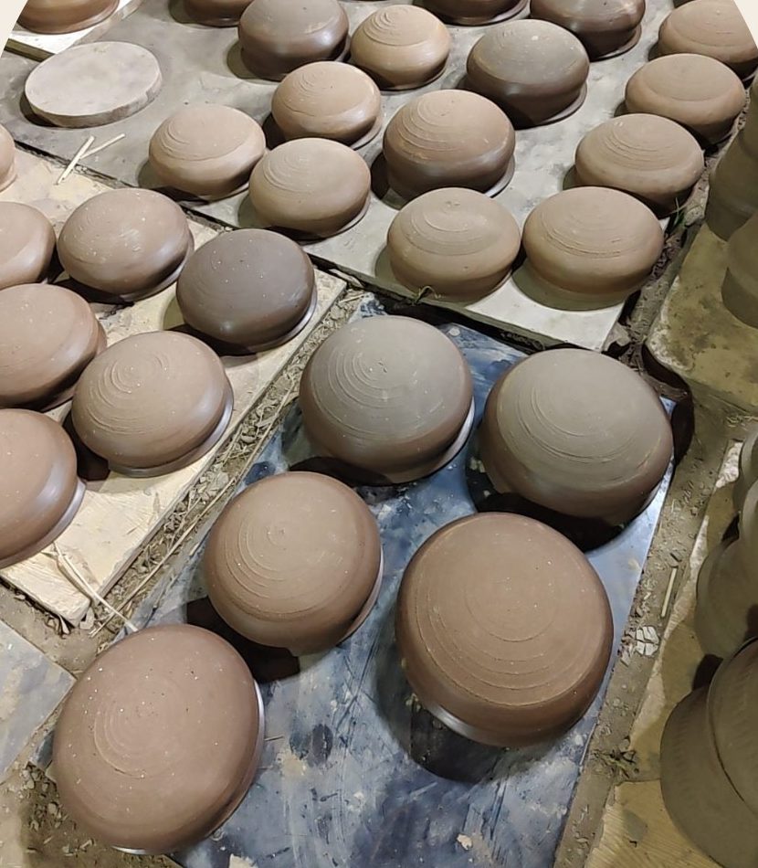 Rows of freshly thrown clay pots drying on the studio floor